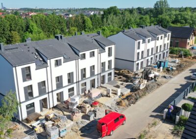 Zaawansowane prace urbanizacyjne przy domach Domy Iwińskie w Iwinach, z widoczną kostką brukową i podjazdami